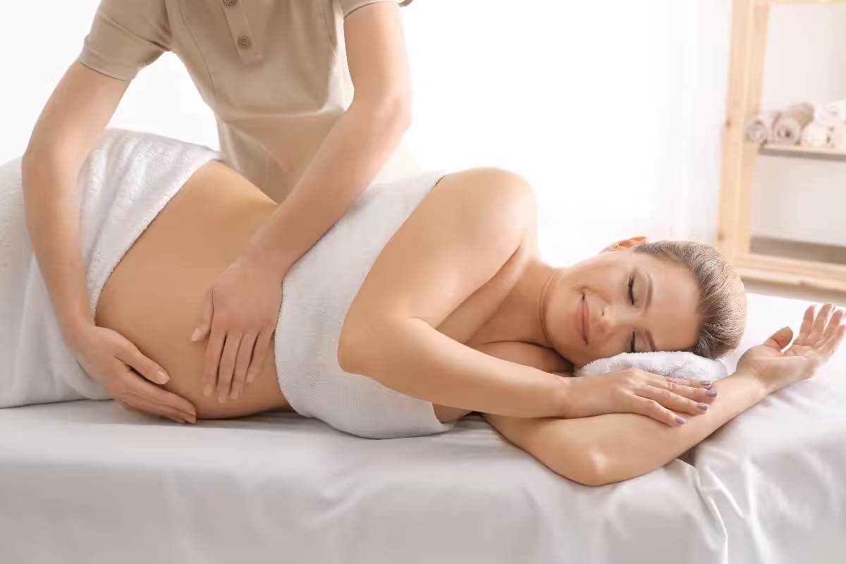 Young beautiful pregnant woman having massage in spa salon